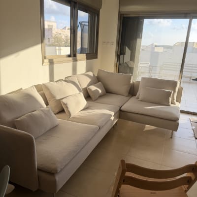 סלון עם ספה וכיסא עץ ליד חלון גדול