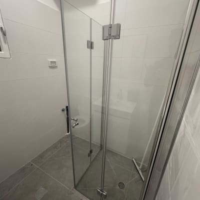 מקלחון זכוכית עם דלתות סגורות ורצפת אריחים אפורה