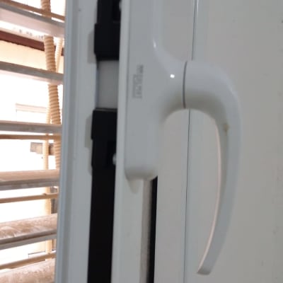 ידית חלון לבנה עם תריסים ברקע