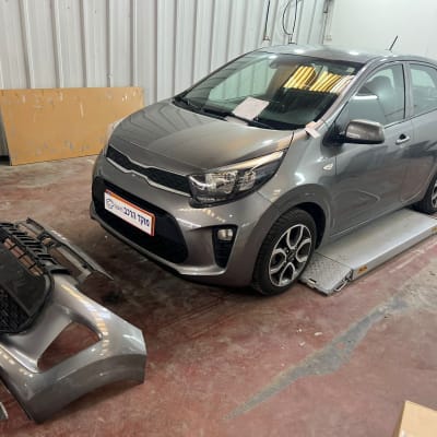 רכב אפור עם פגוש מנותק במוסך תיקונים