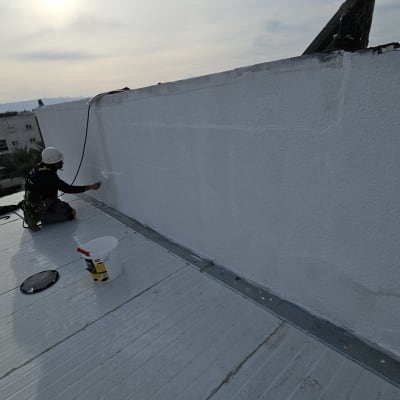 אדם צובע קיר חיצוני על גג עם רולר צבע