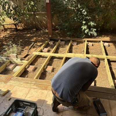 אדם עובד על בניית דק עץ בגינה