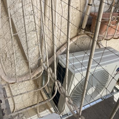 יחידת מיזוג אוויר מותקנת על קיר חיצוני עם צינורות.