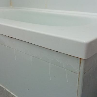 אמבטיה עם חיפוי אריחים לבנים ונזילות מים