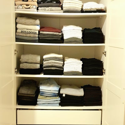 ארון בגדים מסודר עם בגדים מקופלים ומגירה פתוחה