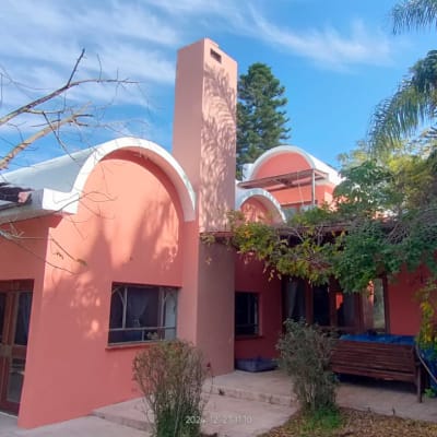 בית ורוד עם גג קשתות ועצים מסביב