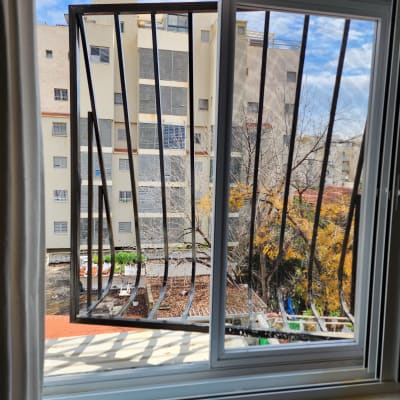 חלון עם סורגים מתכתיים פתוחים מול בניין