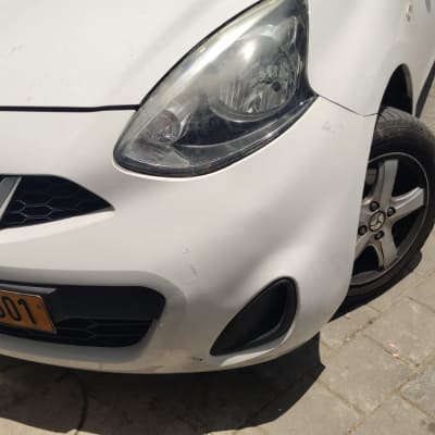 חזית רכב לבן עם פנס קדמי וגלגל