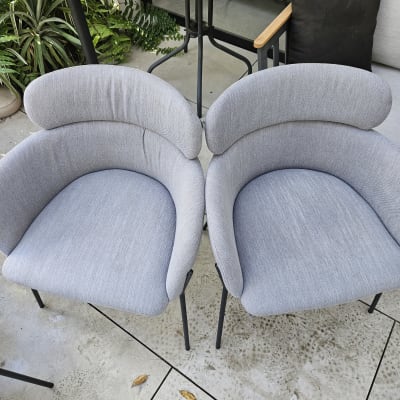 שני כיסאות אפורים על רצפת בטון עם עלים יבשים