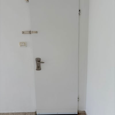 דלת לבנה עם ידית מתכת על קיר לבן