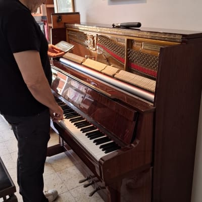 אדם מכוון פסנתר עם כלים לידו