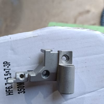 חלק מתכת קטן עם חורים, מונח על קרטון