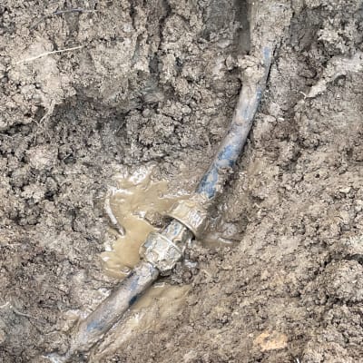 צינור מים שבור באדמה בוצית