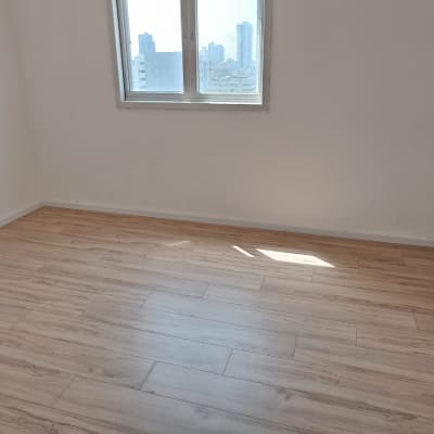 רצפת פרקט עץ בהירה בחדר ריק עם חלון