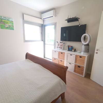 ארון עם סלסלות קש, מאוורר, טלוויזיה על הקיר