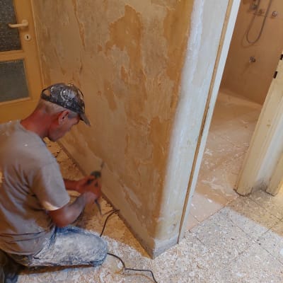 אדם משייף קיר עם מכשיר חשמלי