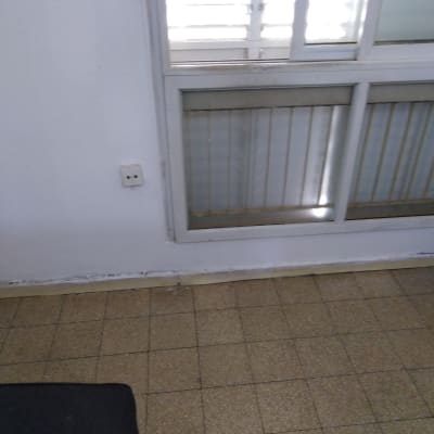 קיר לבן עם סימני צבע מתקלפים ליד חלון