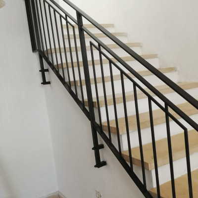 מעקה מתכת שחור על מדרגות עץ בהירות