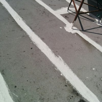 פסי איטום לבנים על גג אפור עם סולם מתכת