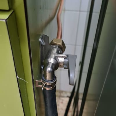 שסתום מתכת עם צינור גומי מחובר לקיר