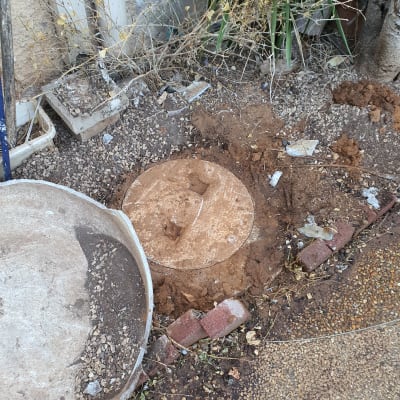 מכסה ביוב עגול באדמה עם לבנים מסביב