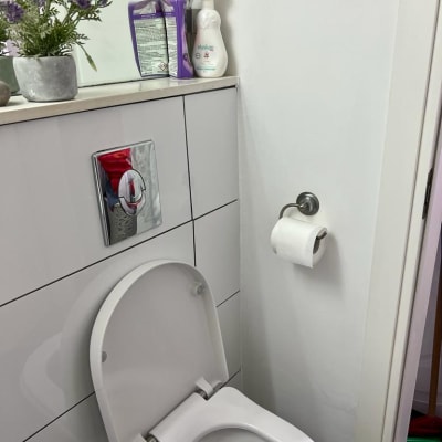 חדר שירותים עם אסלה, נייר טואלט ומוצרי ניקוי על מדף