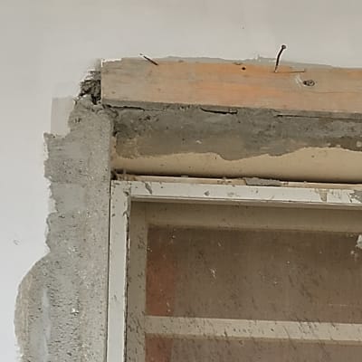 מסגרת חלון עם בטון חשוף ומסמרים בולטים