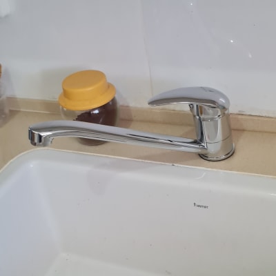 ברז מטבח כסוף מעל כיור לבן עם מגב כתום