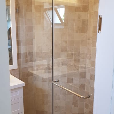 מקלחון זכוכית עם דלת פתוחה ורצפת אריחים