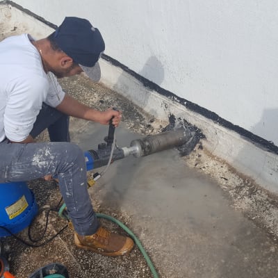 אדם קודח חור בגג עם מקדחה חשמלית