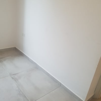 קיר לבן צבוע עם רצפת אריחים אפורה