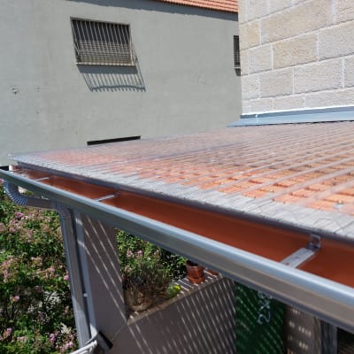 גג פלסטיק שקוף עם מרזב מתכת בגינה