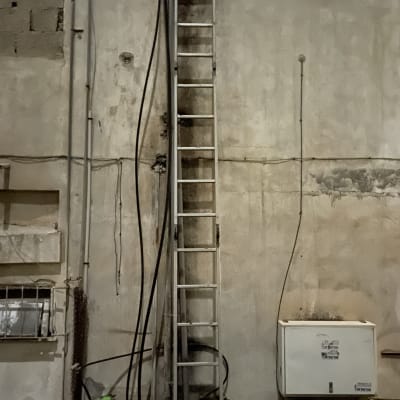סולם מתכת צמוד לקיר עם צינורות חשמל