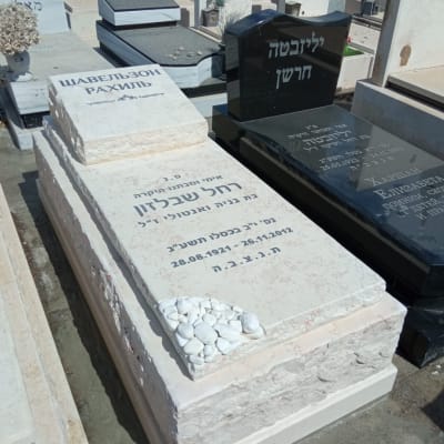 מצבות עם כיתוב בעברית ואבנים לבנות על אחת מהן