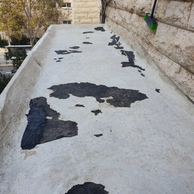 גג עם כתמים שחורים ומטאטא ירוק תלוי על הקיר