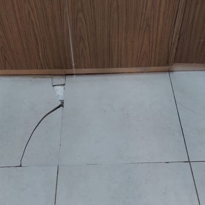 רצפה עם אריחים שבורים ליד קיר עץ