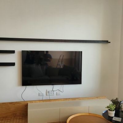 טלוויזיה תלויה על הקיר עם מדפים שחורים