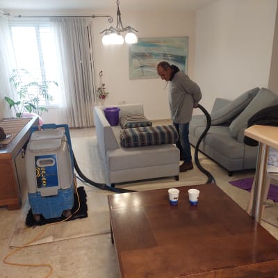 אדם מנקה ספה עם מכונת ניקוי מקצועית