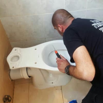 אדם מתקן אסלה עם מברג