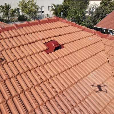 גג רעפים אדום עם פתחי אוורור וצל רחפן