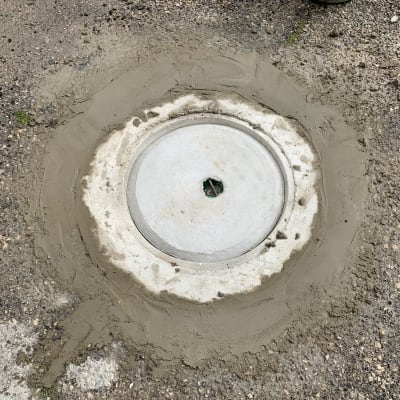 מכסה ביוב עגול מוקף בטון רטוב