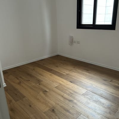 רצפת פרקט עץ בחדר ריק עם קירות לבנים