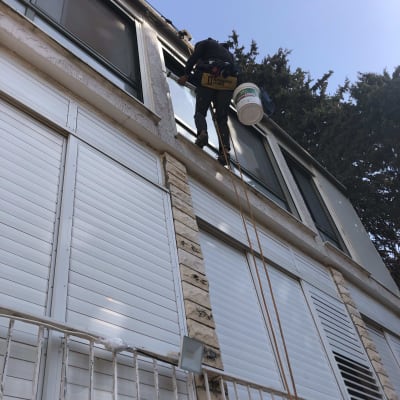 אדם מנקה חלונות בגובה עם ציוד בטיחות