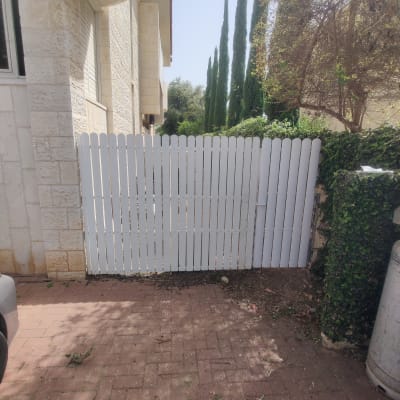 גדר עץ לבנה עם שביל מרוצף ליד גינה