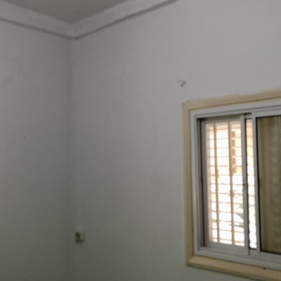 קיר צבוע עם חלון ויריעת מגן ירוקה על הרצפה