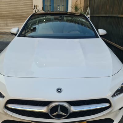 מכונית מרצדס לבנה עם סמל על מכסה המנוע