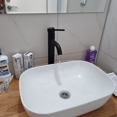 כיור עם ברז שחור זורם על משטח עץ