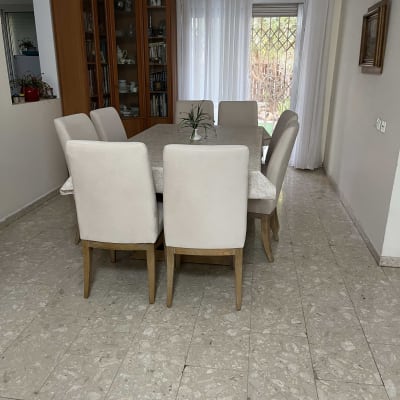 כיסאות מרופדים סביב שולחן אוכל בחדר אוכל מואר