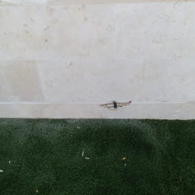 ברז מים מותקן על קיר אבן מעל דשא סינתטי