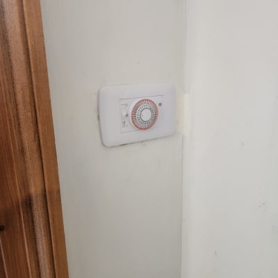 טיימר מכני על קיר לבן ליד דלת עץ